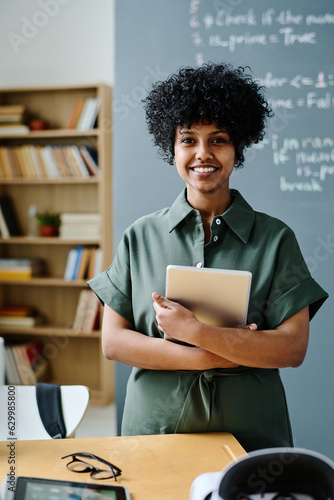 Portrait of young African American IT teacher with tablet pc smiling at camera while standing in class