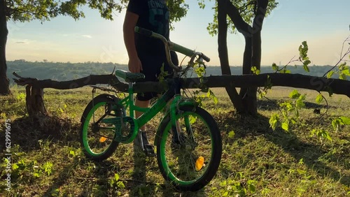 A boy near a bicycle in a beautiful forest at sunset. photo