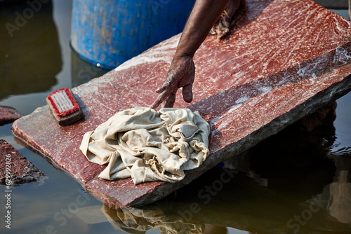 laundry workers at the Jamuna River in Agra near the famous Taj Mahal. Lots of colorful dirty clothes washed in chemicals for very little pay