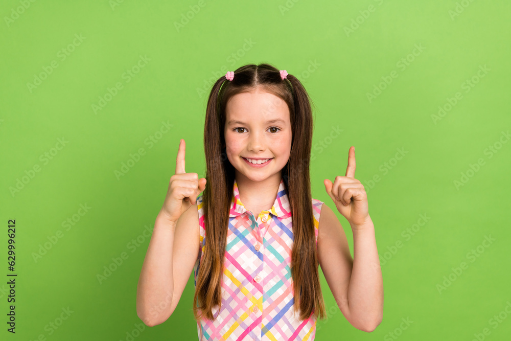 Photo of cheerful lovely schoolkid beaming smile indicate fingers up empty space isolated on green color background Photo of cheerful lovely schoolkid beaming smile indicate fingers up empty space isolated on green color background