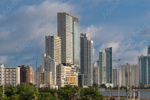 City skyline with many tall highrise office, business and condo skyscrapers at the waterfront by ocean, shot on a sunny day from Old City Fort walls, Cartagena Colombia.