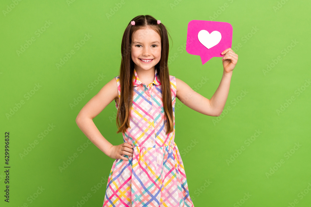Photo of pretty cheerful girl wear stylish clothes hand hold heart card positive feedback isolated on green color background Photo of pretty cheerful girl wear stylish clothes hand hold heart card positive feedback isolated on green color background