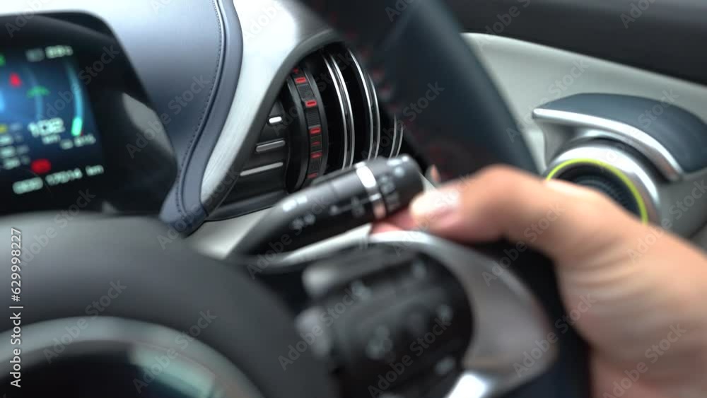 Clos-up action of a car driver hand is swtich the signal lever behind steering wheel to turn-on the turning light. Transportation safety action 4k footage. Clos-up action of a car driver hand is swtich the signal lever behind steering wheel to turn-on the turning light. Transportation safety action 4k footage.