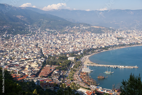 Enjoy the stunning view of Alanya from the observation deck, with lush trees, blue sea, and the iconic Lighthouse and Port of Alanya. The rocky peninsula adds a dramatic touch to the panoramic scene. © Анатолий Савицкий