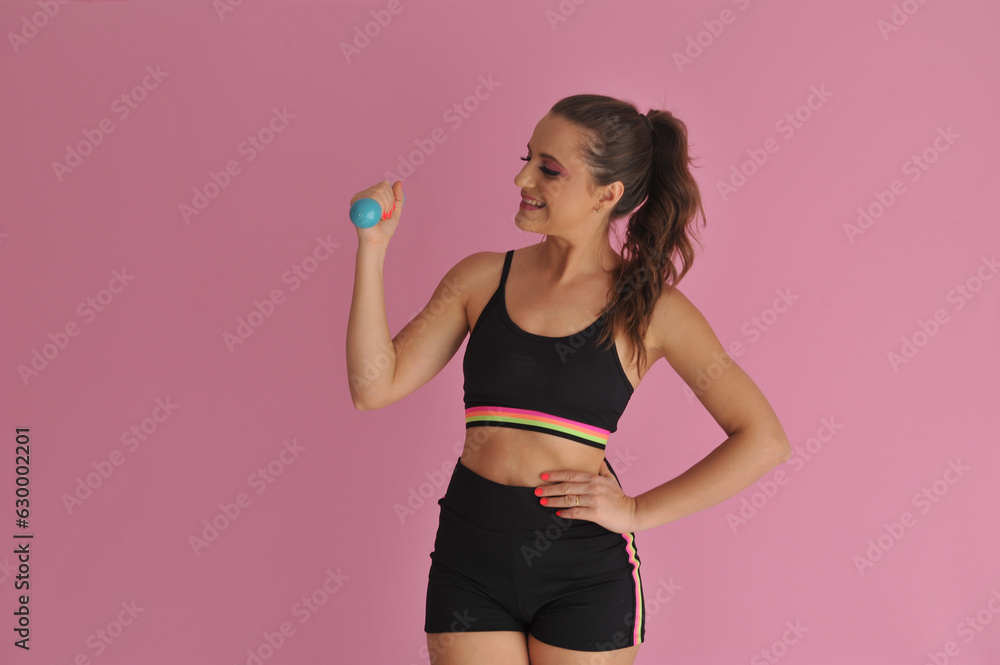 mulher com roupa de treino fitness segurando peso de academia em fundo rosa mulher com roupa de treino fitness segurando peso de academia em fundo rosa