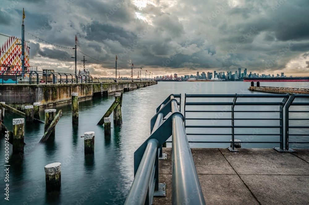 A long exposure of North Vancouver shipyard pier with poles on the water and a big cloudy sky A long exposure of North Vancouver shipyard pier with poles on the water and a big cloudy sky
