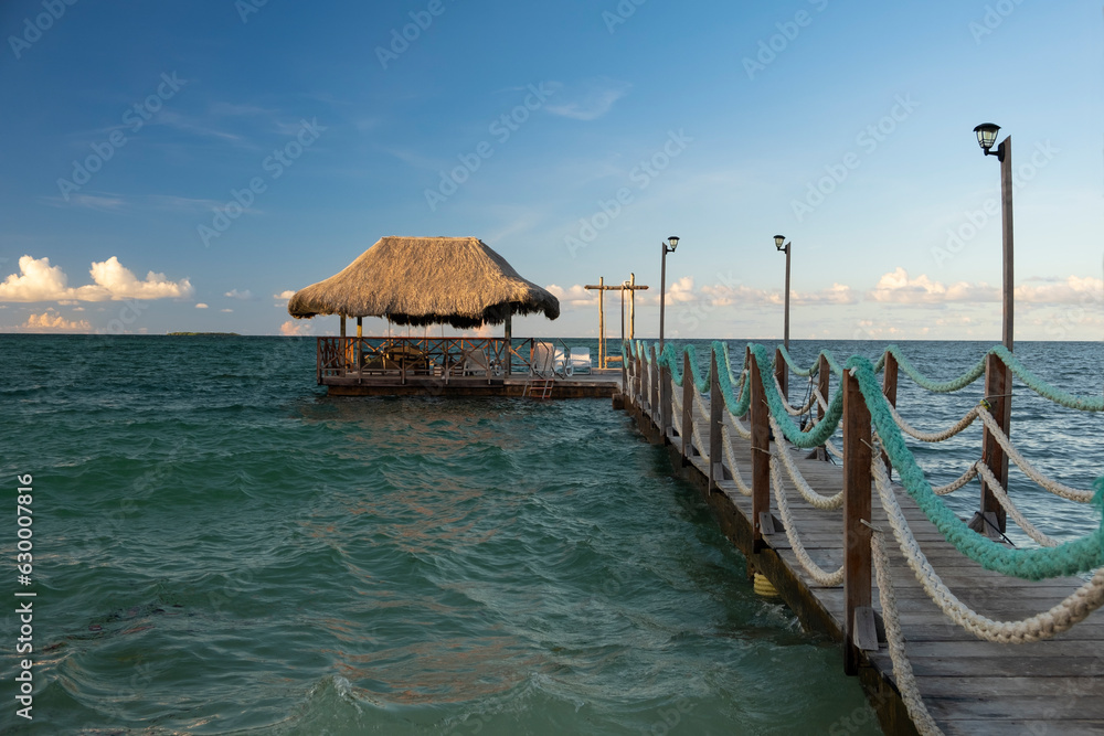 Wooden pier going far into the ocean with a boat dock at the end, Rosario Islands, Cartagena, Colombia. Shot in early morning, blue sky, sunny day.
