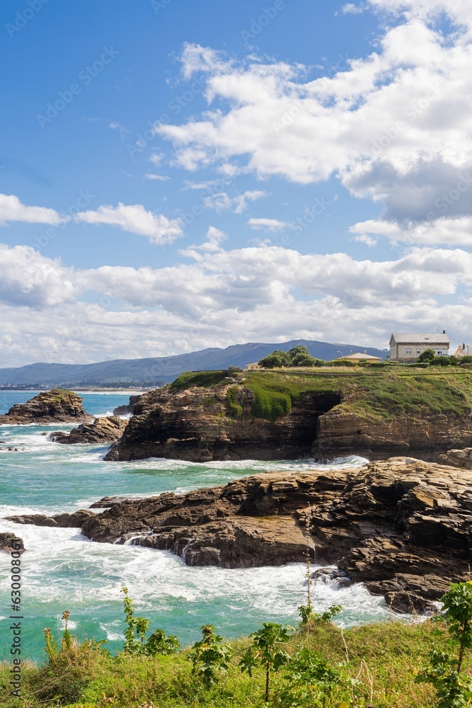 Vertical shot of rocky cliffs and stone formations near the shore in Galicia, Spain