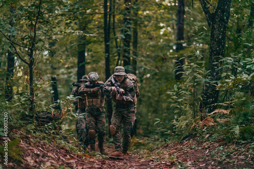 A group of modern warfare soldiers is fighting a war in dangerous remote forest areas. A group of soldiers is fighting on the enemy line with modern weapons. The concept of warfare and military © .shock