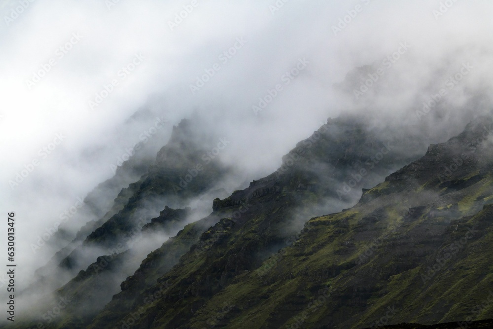 Scenic landscape on a cloudy day featuring a majestic mountain range in fog, Iceland