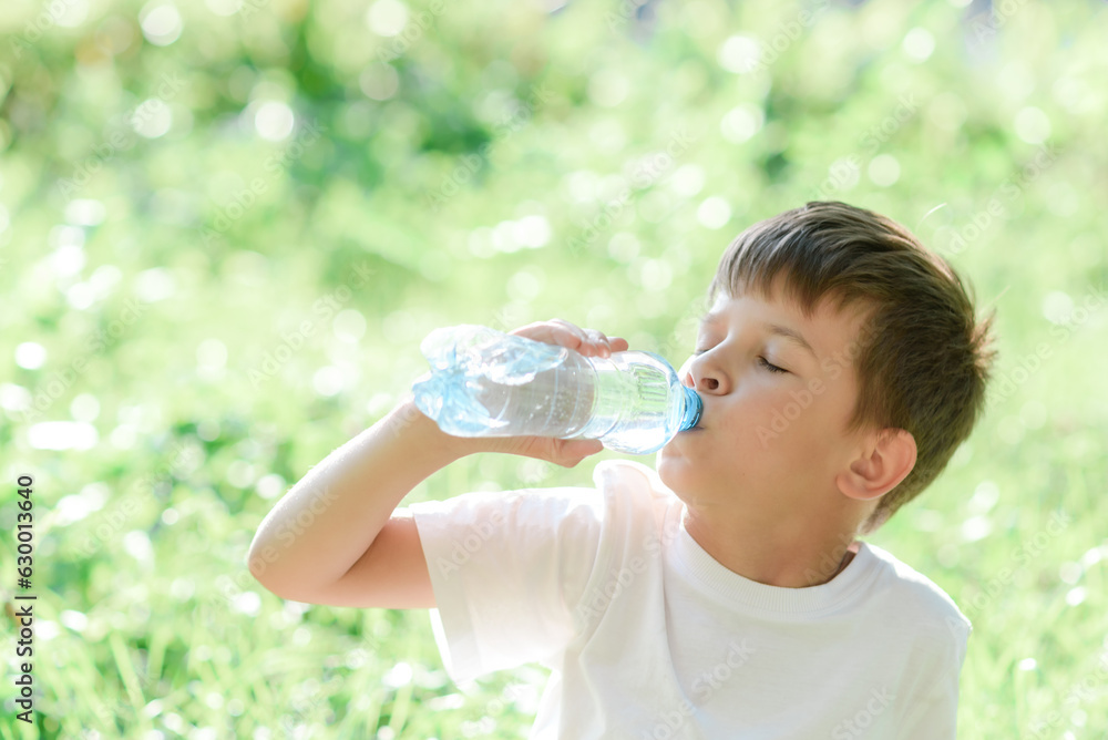 Cute child drinks water from a bottle on the street in summer Cute child drinks water from a bottle on the street in summer