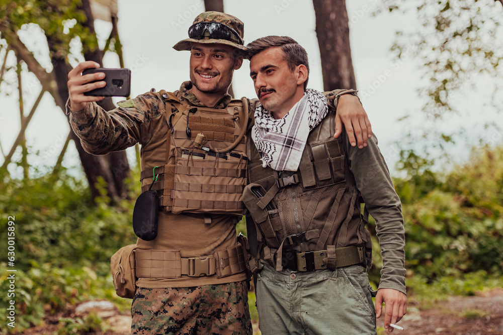 Team of soldiers and terrorist taking selfie with smartphone in the forest Team of soldiers and terrorist taking selfie with smartphone in the forest