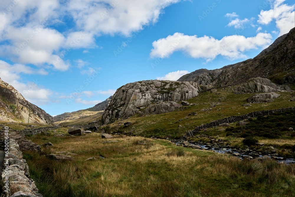 Landscape of hills covered in greenery under the sunlight and a blue cloudy sky