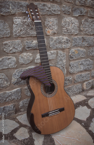 Spanish guitar leaning against a stone wall with a 