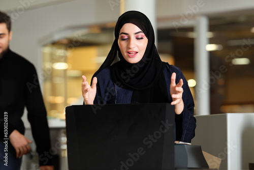 Arabic using computer laptop for business, school education or finance concept Arab woman wearing Abaya Hijab Emirati at an indoor location, shopping mall, coffee shop or office hall