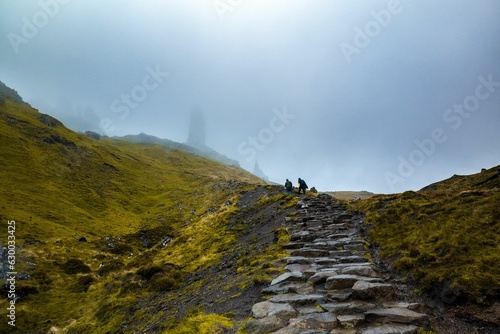 Canvas Print people climbing up a steep mountain on a foggy day