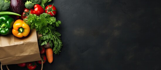 Top view of a paper bag filled with raw vegetables and fresh fruit on a dark background, with space