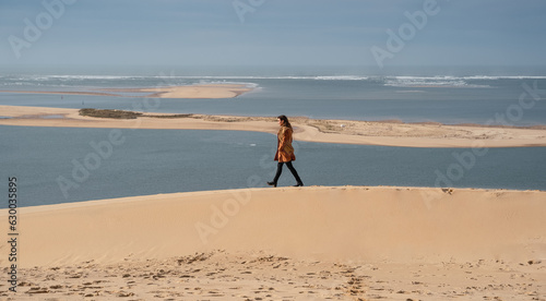 Obraz na płótnie Woman walking in the French dunes in winter, wearing a coat. w salonie