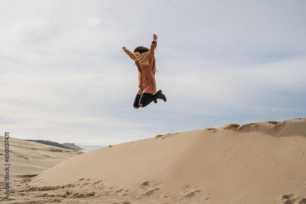 Woman jumping in the French dunes in winter.