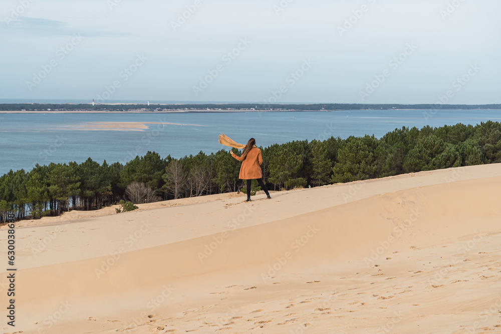 Woman walking in the French dunes in winter, wearing a coat.