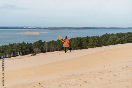 Woman walking in the French dunes in winter, wearing a coat.