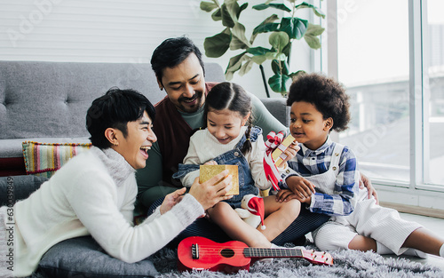 Quadro em tela Couple male gay taking care, giving gift to adopted caucasian daughter girl with love and happiness to celeblate birthday in living room at home