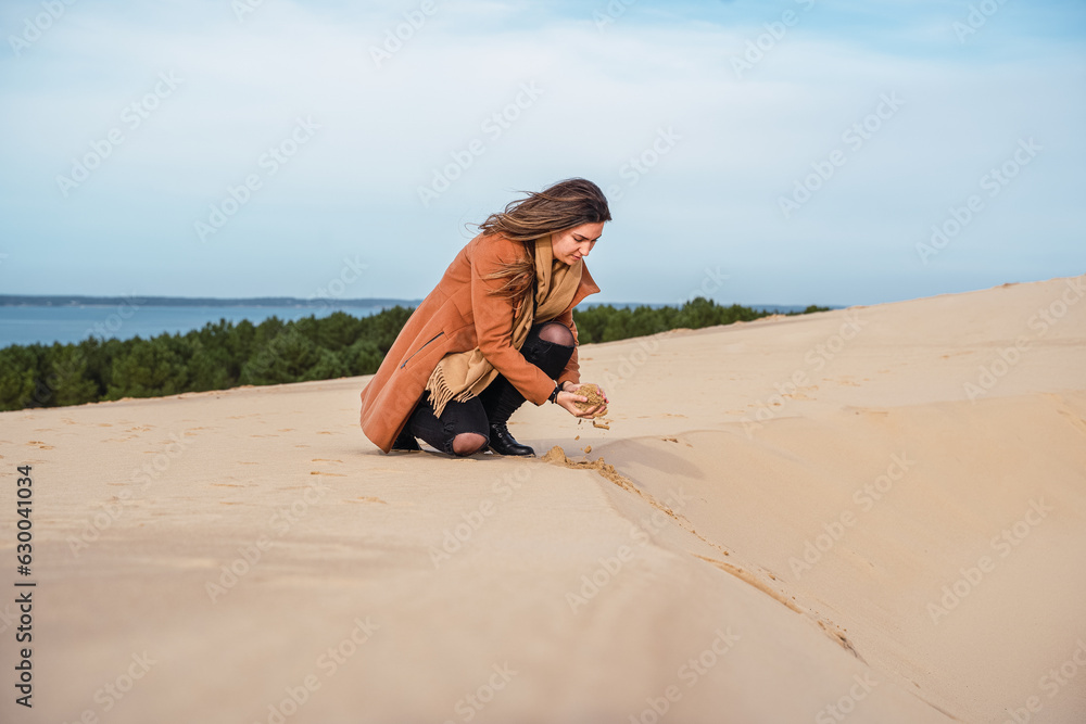 Woman on French dune collects golden sand