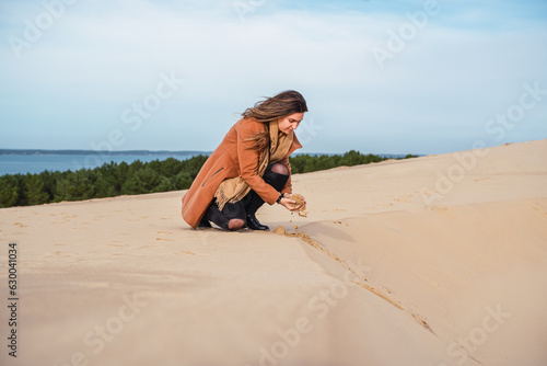 Obraz na płótnie Woman on French dune collects golden sand w salonie