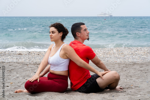 Young couple of woman and man meditation together on the beach