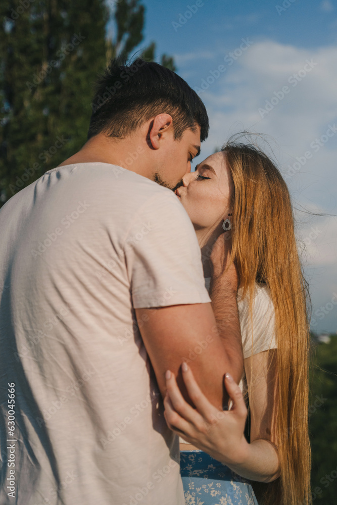 Young beautiful couple attractive boy and girl posing and kissing on a country field. Peace and freedom in nature Young beautiful couple attractive boy and girl posing and kissing on a country field. Peace and freedom in nature