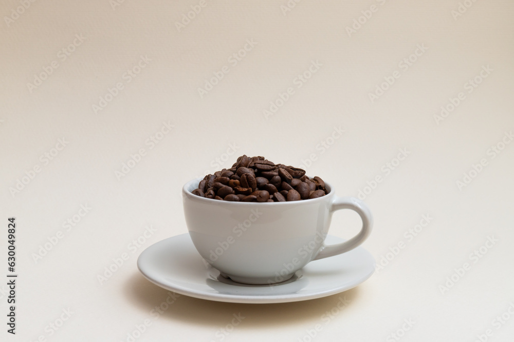 White cup filled with coffee beans isolated on cream background