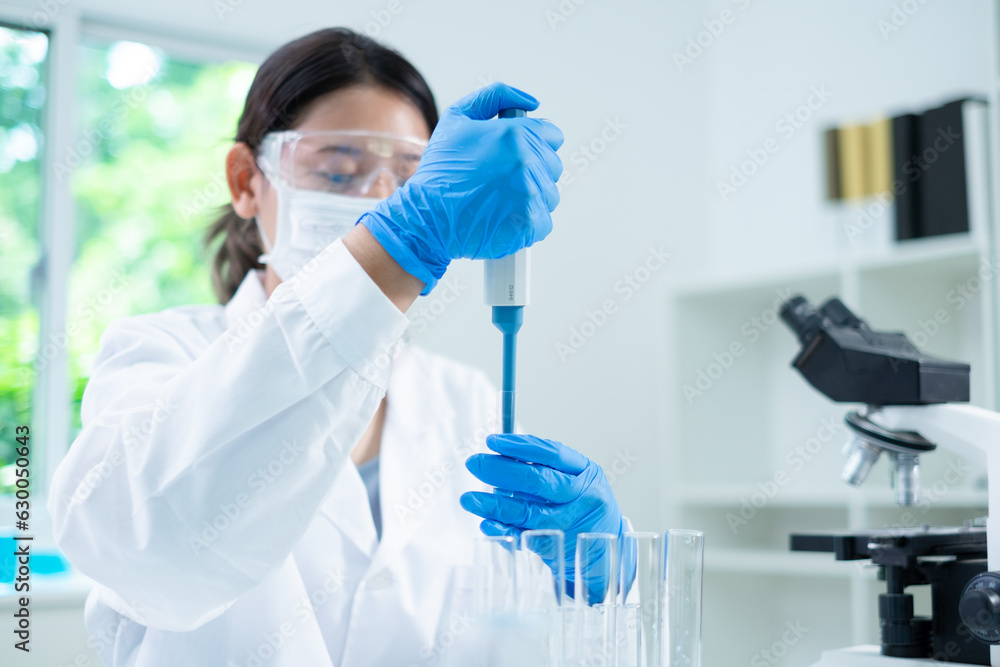 Φωτογραφία Asian woman scientist is dropping blue liquid substance in science test tube in laboratory