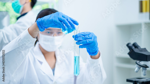 Close up of female scientist or researcher is pouring blue substance or liquid into sample test tube. Concept of science, biochemistry, chemical laboratory. Substance study analyzing experiment.