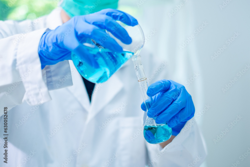 Close up of Female scientist or researcher is pouring blue substance or liquid in to a sample test tube. Concept of science, biochemistry, chemical, biotechnology laboratory. Analyzing and experiment Close up of Female scientist or researcher is pouring blue substance or liquid in to a sample test tube. Concept of science, biochemistry, chemical, biotechnology laboratory. Analyzing and experiment
