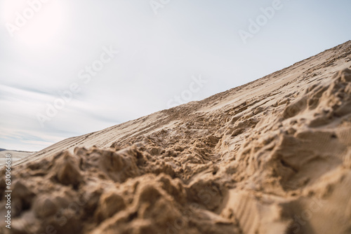 Obraz na płótnie footprints in the sand, in black boots and brown coat, walking in the dunes. w salonie