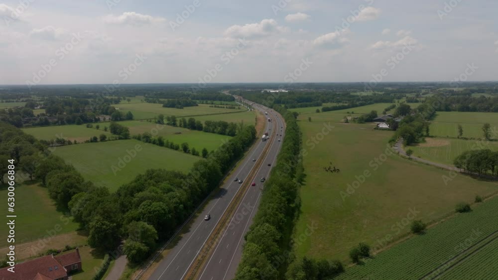 Drone view on landscape and cars driving on highway through small forrests and open fields in the Netherlands, Europe. Drone view on landscape and cars driving on highway through small forrests and open fields in the Netherlands, Europe.