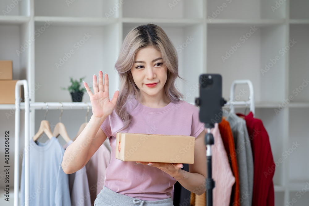 Young woman selling goods product clothes dress shirt online by smartphone live streaming video interaction internet online shop and talking to camera Young woman selling goods product clothes dress shirt online by smartphone live streaming video interaction internet online shop and talking to camera