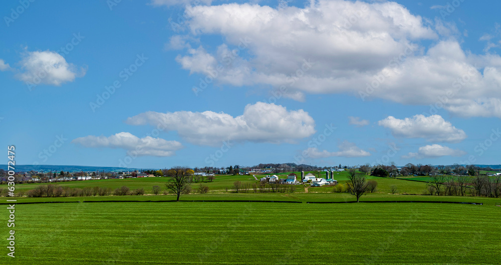 An Aerial View of Countryside, with Farms, Green Crops, Trees, Borders, Barns and Silos. on a Sunny Spring Day