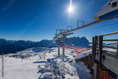 Falcade, Italy - February 15, 2023: At a lift station in the mountains of the Dolomites. Skiers wait in line to take the cable car. Queue of skiers to the lift in ski resort, a lot of people. photo