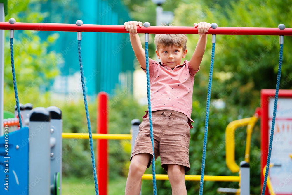 Fototapeta premium Portrait of six year old boy on playground in summer..