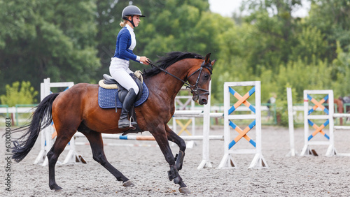 Young woman horseback riding on her show jumping course photo