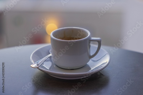 Close up view of coffee cup with saucer and spoon on blurred background isolated.