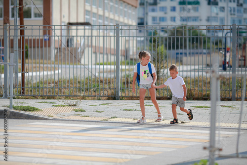 Brother and sister run across a pedestrian crossing. Children Run along the road to kindergarten and school.Zebra traffic walk way in the city. Concept pedestrians passing a crosswalk