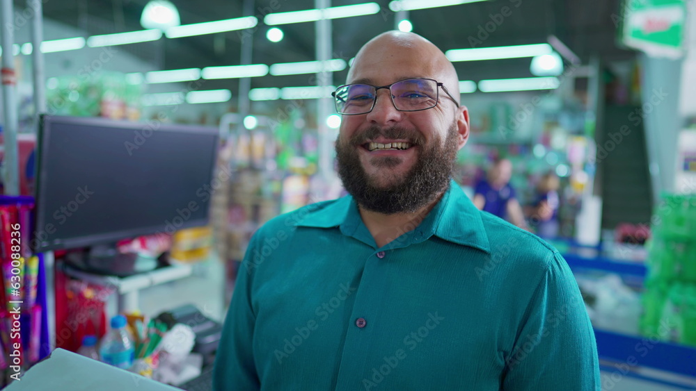 Portrait of a happy Brazilian employee of supermarket standing at checkout smiling at camera. Close-up face of a male staff manager of Grocery Store