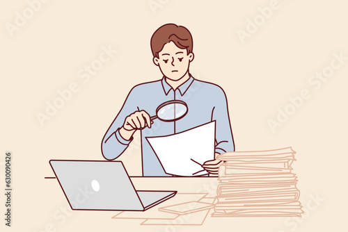 Man tax inspector is sitting in office doing paperwork using magnifying glass to check contract. Financial auditor guy does paperwork, controlling legal purity of transaction and correctness reports