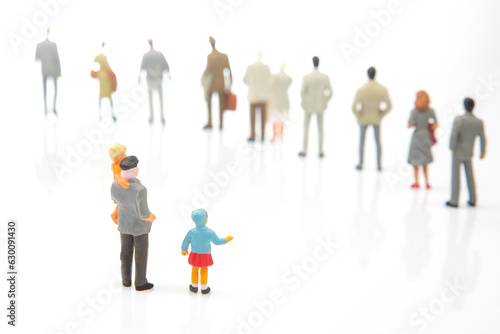 miniature people. little girl with other people stands against the background of other people on a white background. Loneliness and family acceptance in human society. Child care