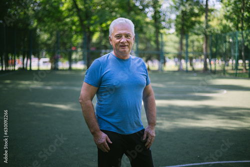 portrait of a senior man over 50 with gray hair in a sports jersey on a sports court © Michael