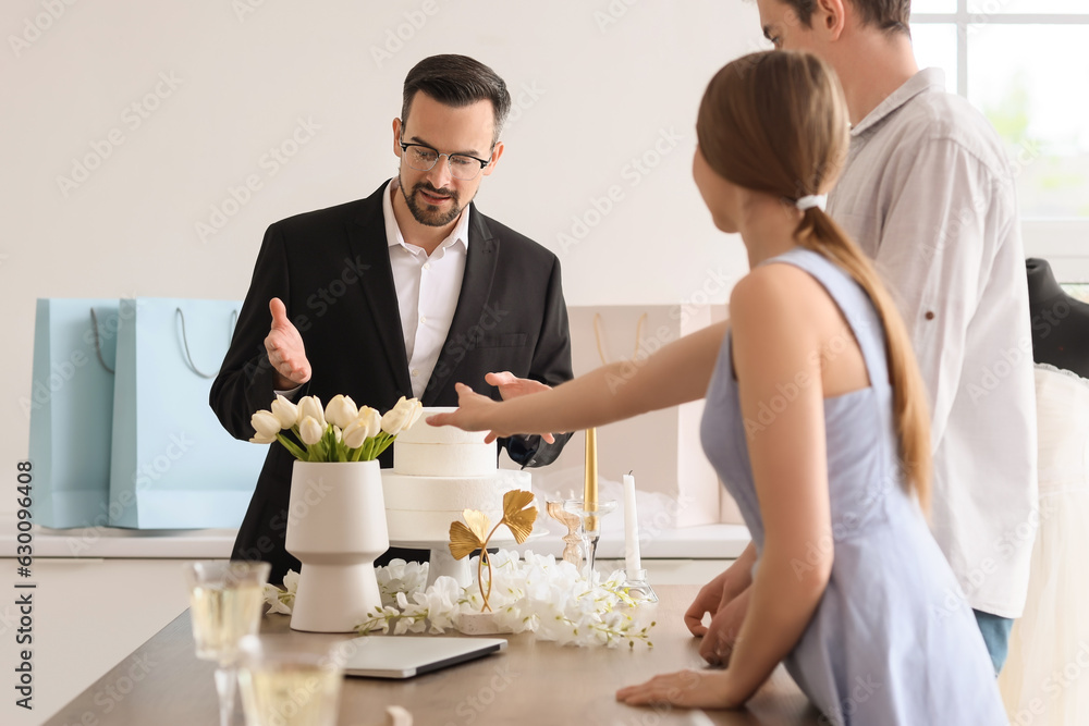 Male wedding planner working with couple in office Male wedding planner working with couple in office