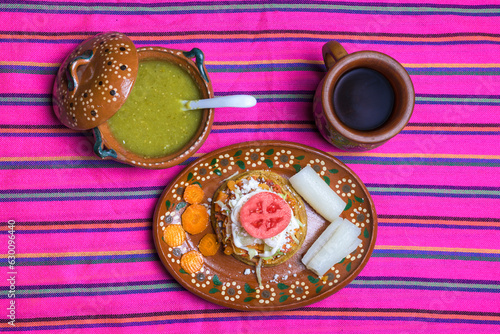 Sope with cheese and tomato accompanied with coffee and green sauce served on a clay plate
