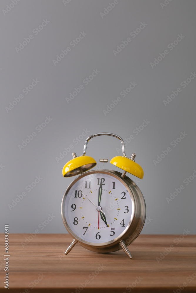 Retro silver alarm clock. 5:00. am, pm. Neutral background. Brown wood surface. Vertical photography with empty space for text or image. Retro silver alarm clock. 5:00. am, pm. Neutral background. Brown wood surface. Vertical photography with empty space for text or image.
